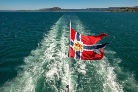 The post symbol on Norwegian flag of a Hurtigruten ship, foaming spray, Trondheimfjord, Agdenes,
