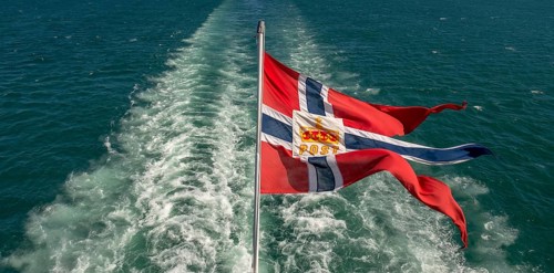 The post symbol on Norwegian flag of a Hurtigruten ship, foaming spray, Trondheimfjord, Agdenes,