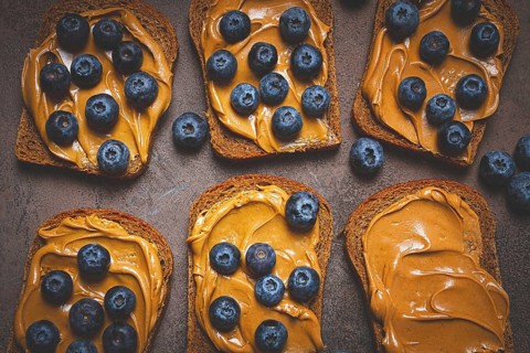 Rye bread with peanut paste and fresh blueberries, top view, no people