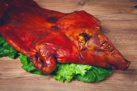 Baked, fried piglet, on a wooden table, no people, The whole piglet is baked and served on the