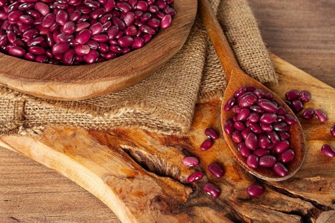 Red beans, laid out in a wooden bowl, on a chopping board, rustic style, covered with burlap, top