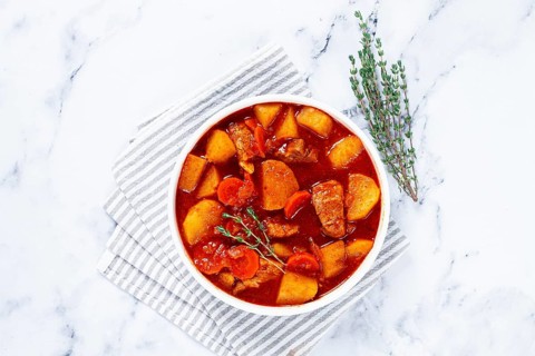 Meat goulash with potatoes and carrots, sweet peppers, in a saucepan, top view, traditional
