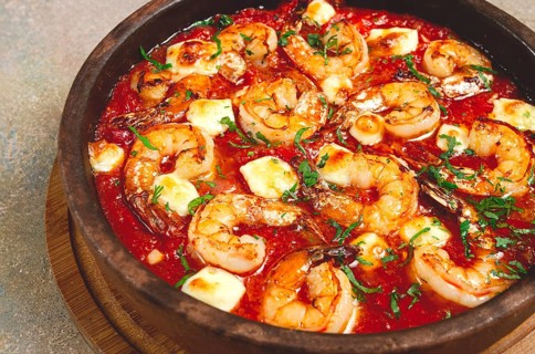 Saganaki with shrimp, in a clay pan, Greek dish, shrimp in tomato sauce, feta cheese, homemade, no