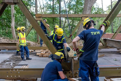 Construction of a temporary bridge over a slipped road crossing a stream, by the bridge