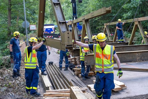 Construction of a temporary bridge over a slipped road crossing a stream, by the bridge