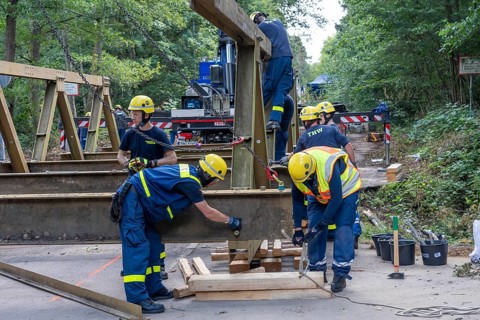 Construction of a temporary bridge over a slipped road crossing a stream, by the bridge