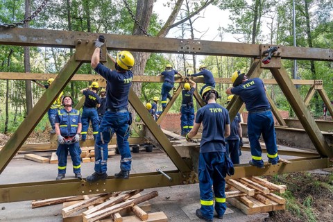 Construction of a temporary bridge over a slipped road crossing a stream, by the bridge