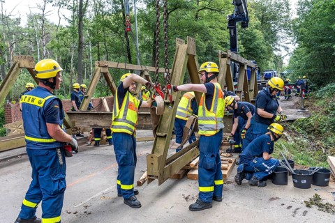 Construction of a temporary bridge over a slipped road crossing a stream, by the bridge