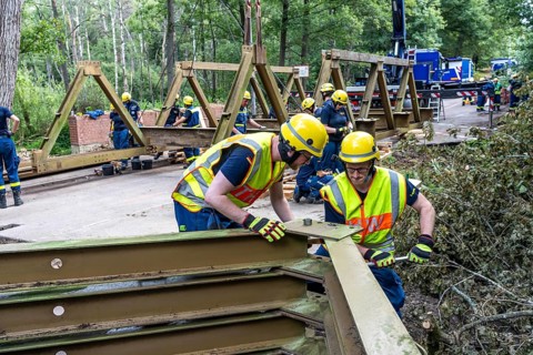 Construction of a temporary bridge over a slipped road crossing a stream, by the bridge