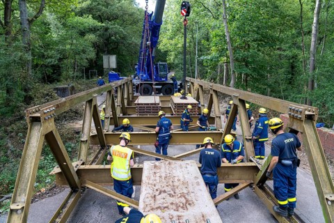 Construction of a temporary bridge over a slipped road crossing a stream, by the bridge