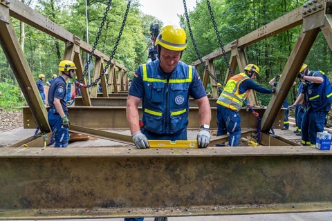 Construction of a temporary bridge over a slipped road crossing a stream, by the bridge