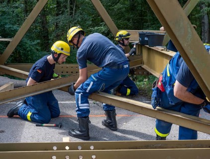 Construction of a temporary bridge over a slipped road crossing a stream, by the bridge