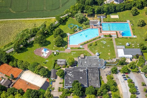 Aerial view, outdoor and indoor swimming pool HeljensBAD with sunbathing lawn, tennis facility of