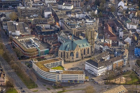 Aerial view, St. Urbanus Catholic Church and church square, commercial buildings and shopping