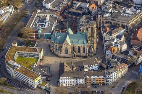 Aerial view, St. Urbanus Catholic Church and church square, commercial buildings and shopping