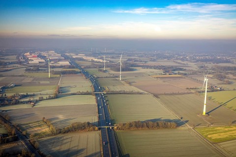 Aerial view, motorway A2, meadows and fields with wind turbines, distant view to the industrial