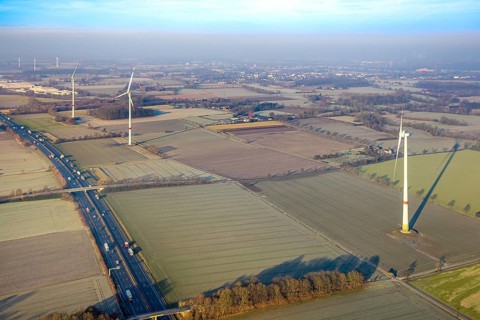 Aerial view, motorway A2, meadows and fields with wind turbines, distant view to the industrial