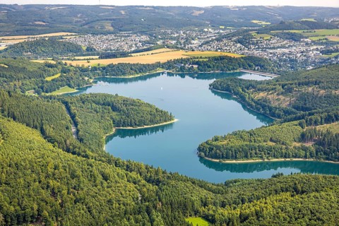Aerial view, Hennesee dam surrounded by forest, Welcome Hotel and view to Meschede, sailing boat on