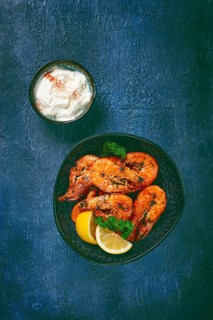Fried white-footed shrimp, tiger prawns vannamey, on a plate, with lemon and herbs, no people