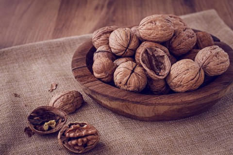 Freshly picked walnuts, in a wooden bowl, on a wooden table, rustic style, no people