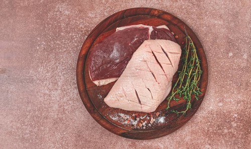Fresh raw duck breasts, on a wooden chopping board, with herbs and spices, no people