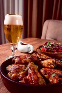 Delicious barbecue chicken wings, with French fries, salad and a refreshing drink, at a cozy table,