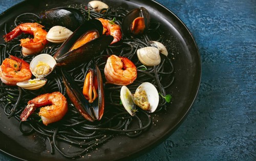 Black spaghetti, with shrimp and mussels, vongole, on a black plate, spaghetti with shrimp,