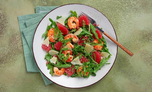 Fresh shrimp salad with arugula, grapefruit, and parmesan served in a bowl