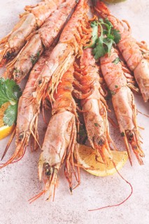 Shrimps on skewers, Grilled, spread on a marble surface, garnished, with lemon slices, and fresh