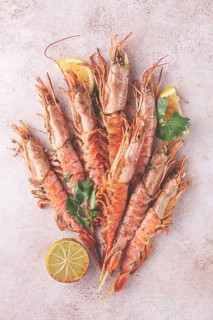 Shrimps on skewers, Grilled, spread on a marble surface, garnished, with lemon slices, and fresh