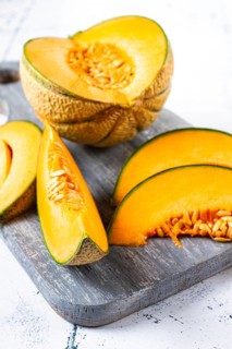 Freshly sliced melon slices, cantaloupe melon, on a wooden chopping board, close-up