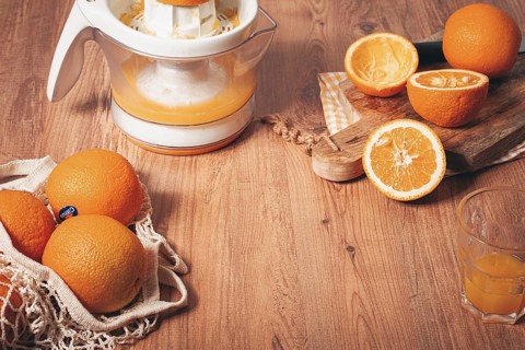 Preparation of freshly squeezed orange juice, using a juicer, in a cozy kitchen setting