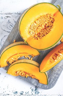 Freshly sliced melon slices, cantaloupe melon, on a wooden chopping board, close-up