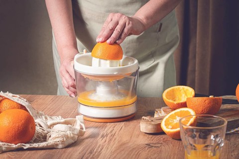 Preparation of freshly squeezed orange juice, using a juicer, in a cozy kitchen setting
