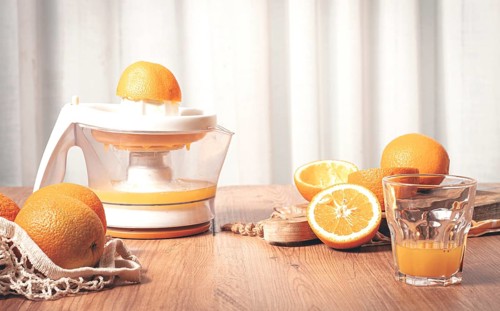 Preparation of freshly squeezed orange juice, using a juicer, in a cozy kitchen setting