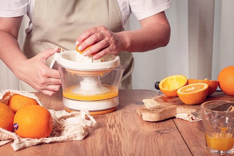 Preparation of freshly squeezed orange juice, using a juicer, in a cozy kitchen setting