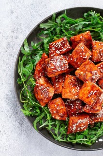 Fried salmon slices, teriyaki with sesame seeds, with arugula salad, top view