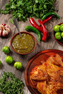 Baked tobacco chicken, served with tkemali sauce, on a wooden table, Georgian cuisine, rustic