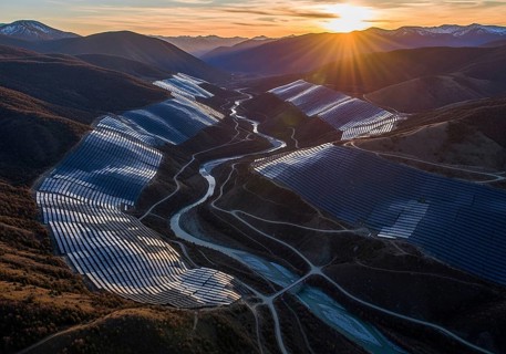 Winding rows of solar panels seamlessly integrated into a mountainous landscape under a dynamic