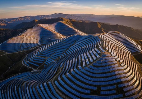 Winding rows of solar panels seamlessly integrated into a mountainous landscape under a dynamic