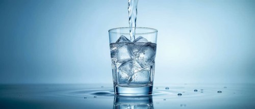 A glass of water with ice cubes being filled with a stream of water, set against a gradient blue