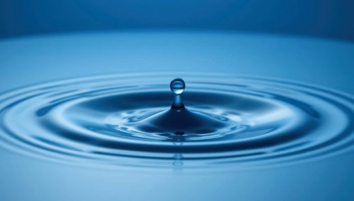 A captivating image of a water droplet creating ripples on a smooth, reflective blue surface,