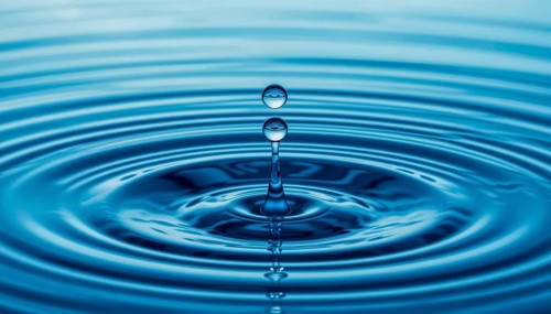 A close-up shot captures the graceful descent of water drops, creating ripples and a mesmerizing