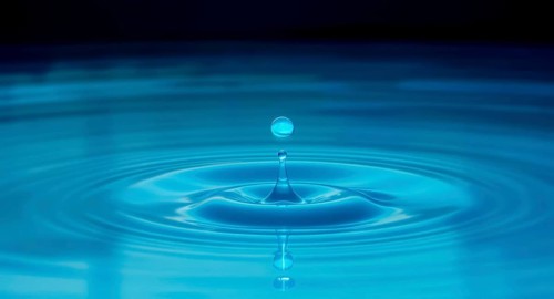 A captivating macro shot of a water droplet creating ripples and reflections, set against a dark
