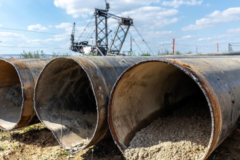 Large excavator in open-cast mine with pipes in the foreground, Manheim, North Rhine-Westphalia,