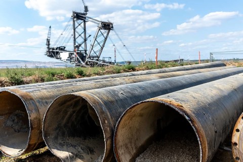 Large excavator in open-cast mine with pipes in the foreground, Manheim, North Rhine-Westphalia,