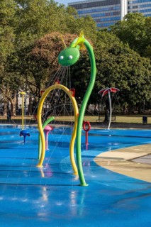 Large green dragon water play equipment with tower block in the background, Cologne, North