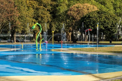Panorama water playground with colourful play equipment, green belt, Cologne