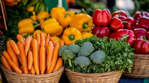 A vibrant display of fresh produce, including carrots, peppers, broccoli, and herbs, artfully