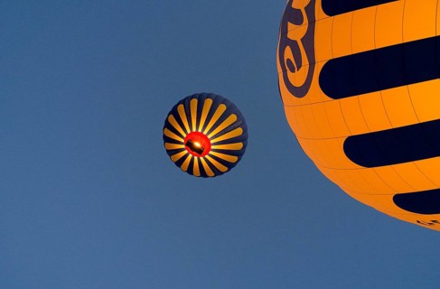 Two yellow-blue hot air balloons floating in front of a clear blue sky, Göreme National Park,